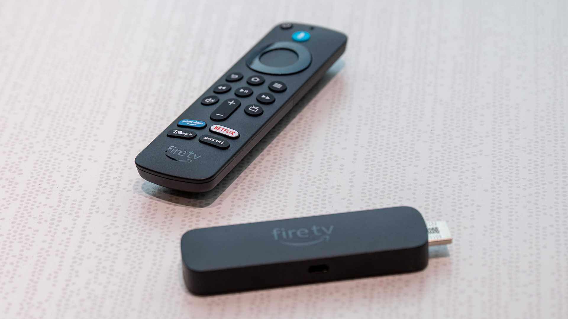Amazon Fire TV Stick 4K Select with its remote sitting on a table.