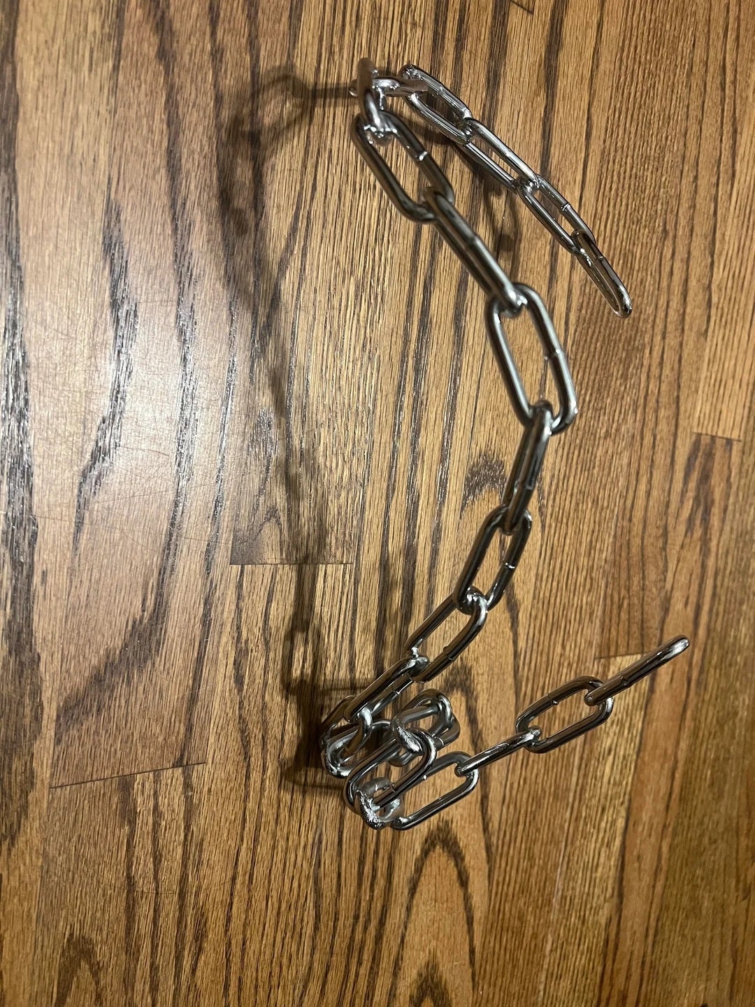Chain links arranged in the shape of a dog on a wooden surface, creating a shadow