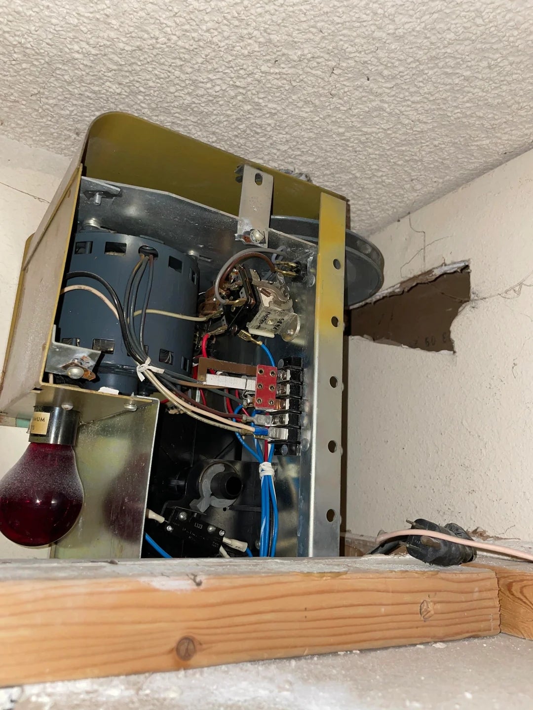Exposed electrical wiring and components inside a partially open metal panel on a ceiling, showing a possibly unfinished repair or installation