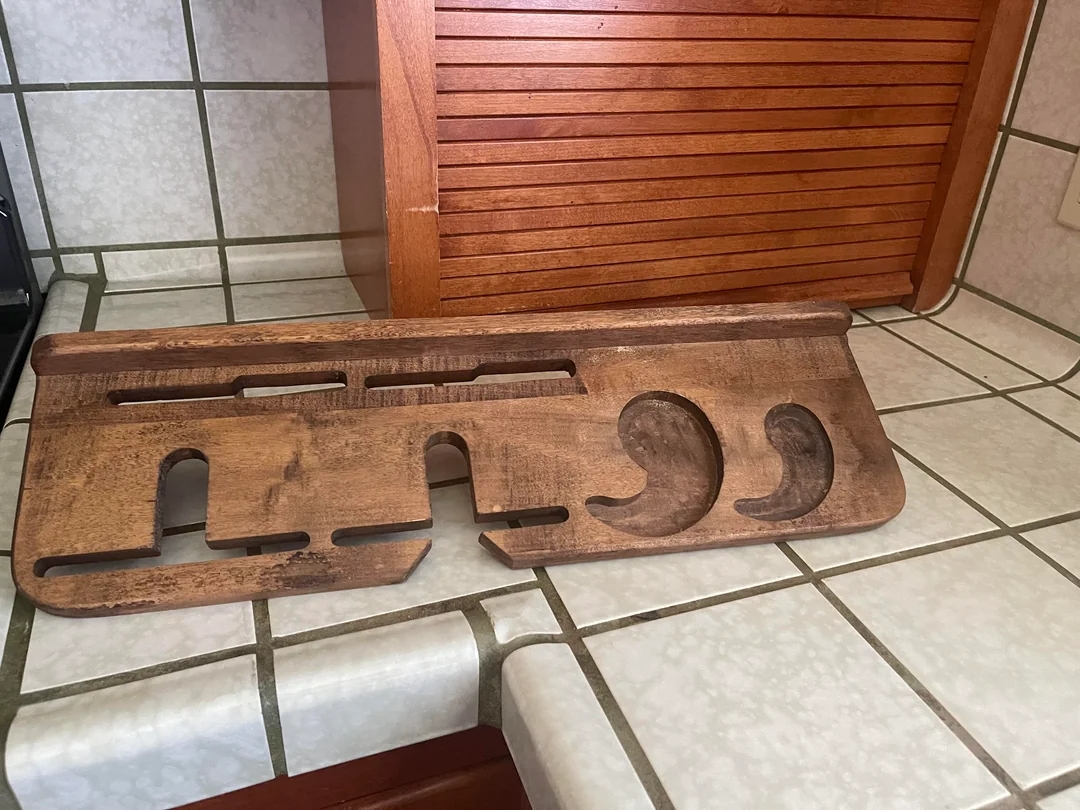 Wooden kitchen rack on a tiled counter, designed to hold knives and utensils, with various cutouts for storage