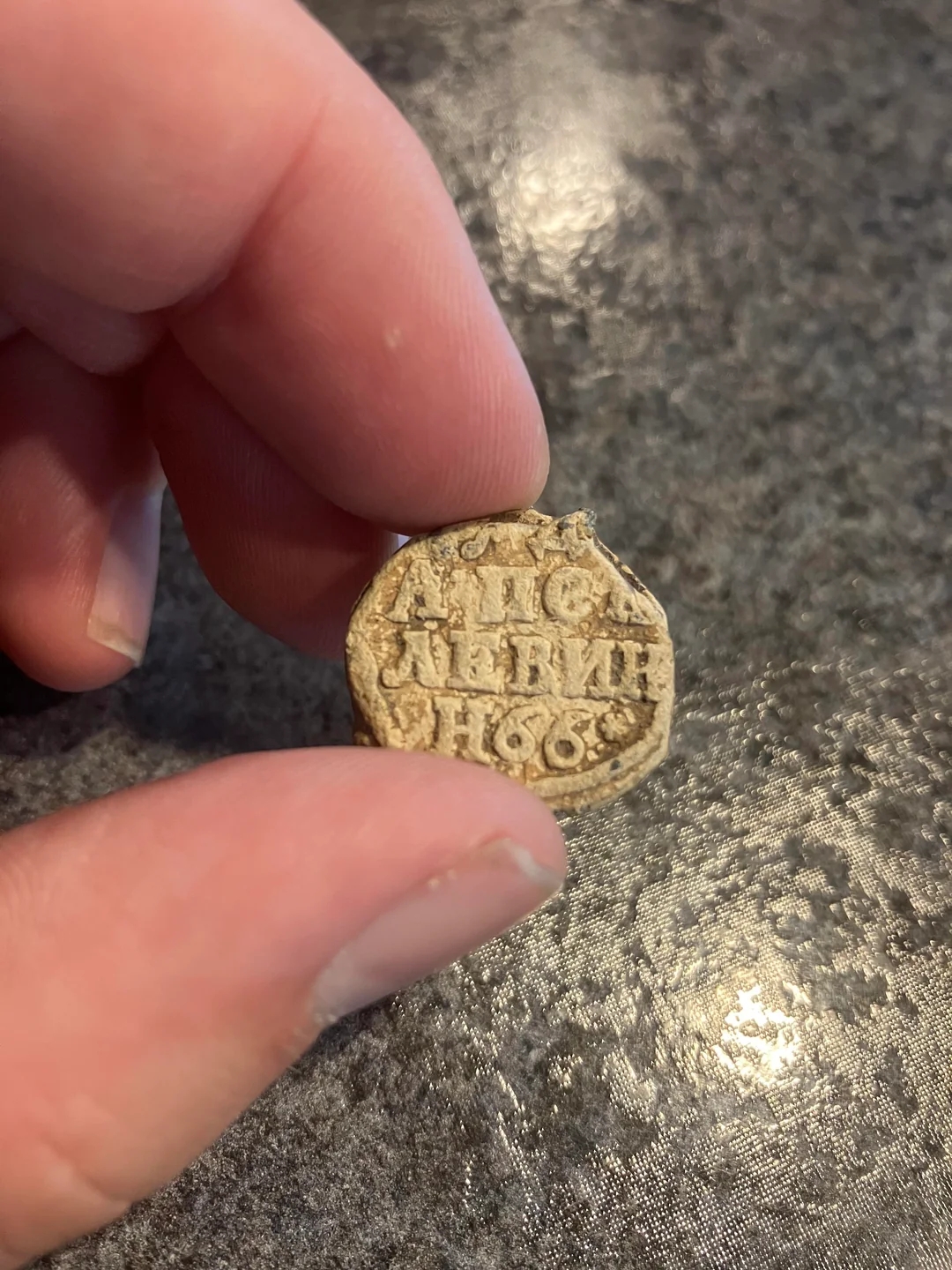 Person holding a small, round object with engraved text reading "1669."