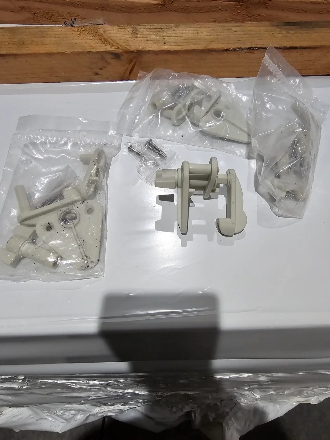 Several plastic wall mounts and brackets in packaging laid out on a white surface