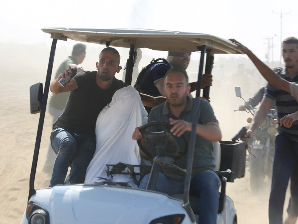  Palestinians transport a captured Israeli civilian from Kfar Azza kibbutz into the Gaza Strip on Saturday, Oct. 7, 2023.