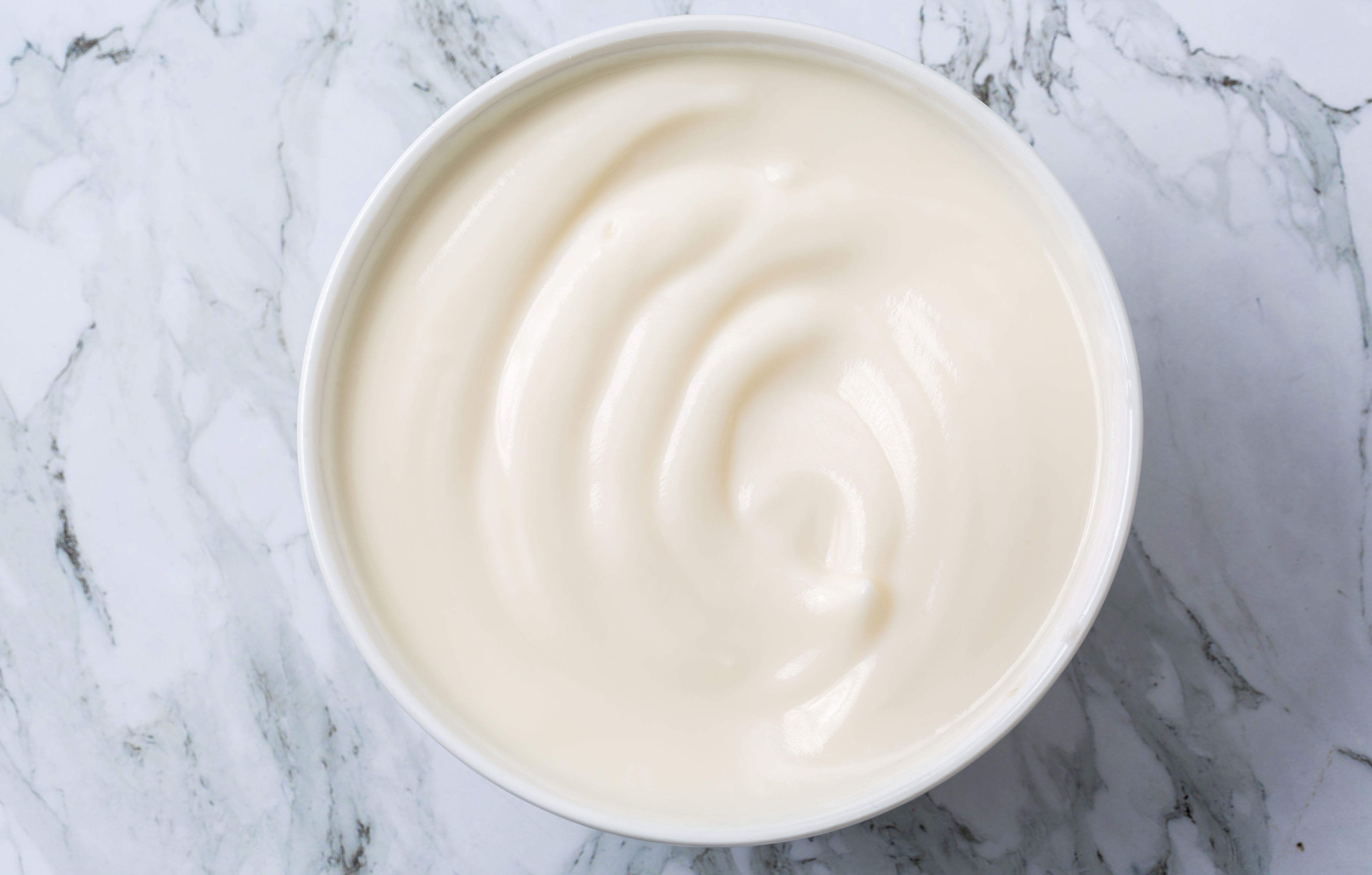 A bowl of creamy yogurt on a marble surface