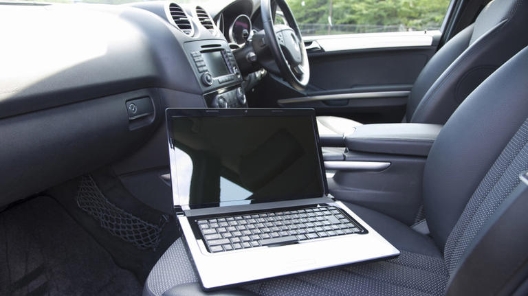 Laptop laying on passenger seat in vehicle interior