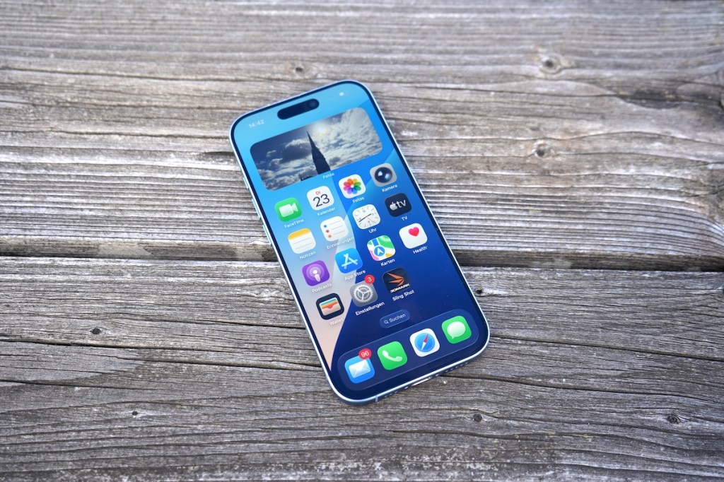 Ein eingeschaltetes iPhone 17 liegt auf einem Holztisch.