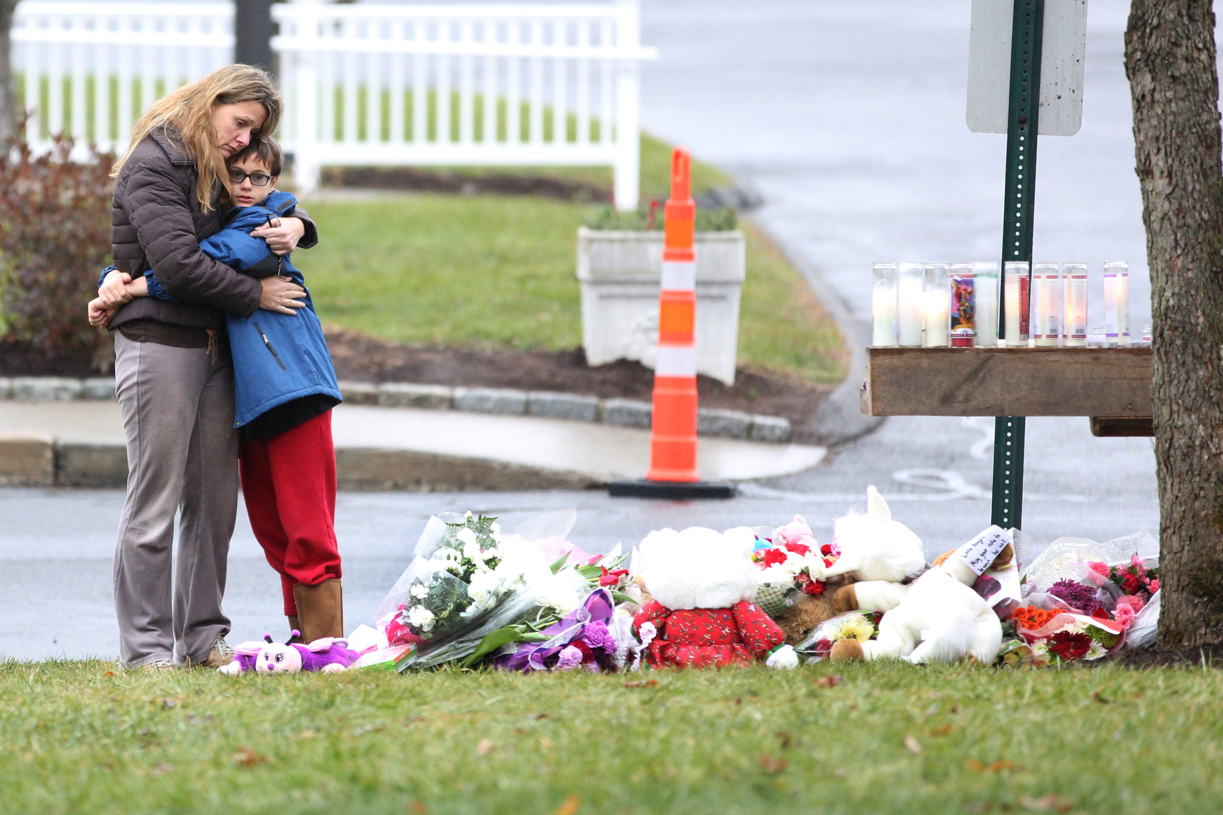 A mother hugs her 10-year-old son at a shrine for victims at St. Rose of Lima Church in Sandy Hook in December 2012. / Corbis via Getty Images