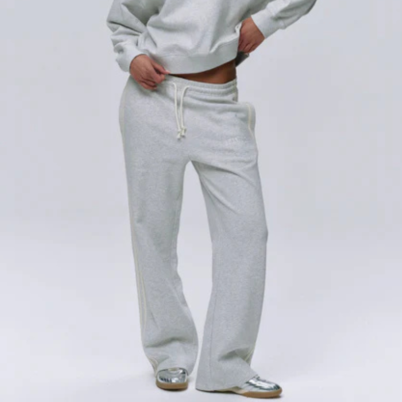 A woman wearing grey tracksuit bottoms and silver trainers
