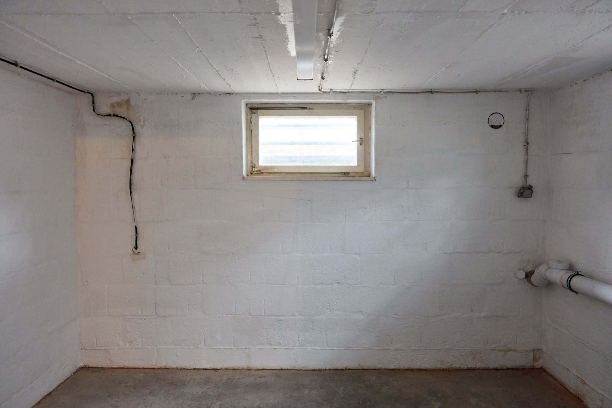 Empty room in the basement with a window as a boiler room or drying room
