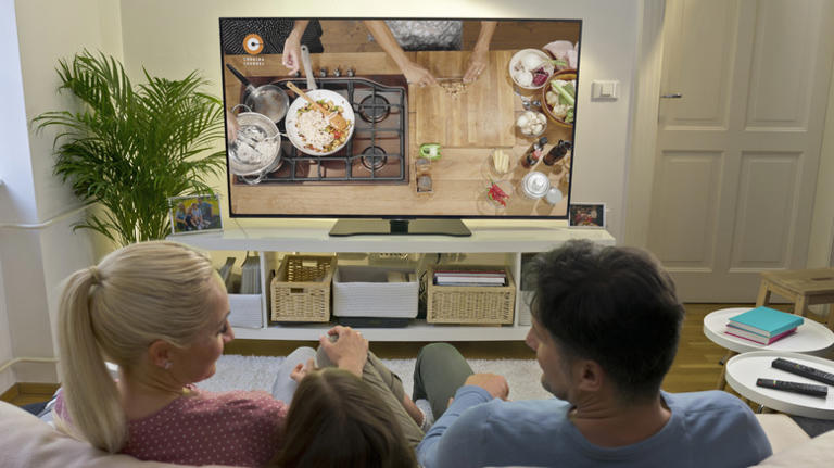 Family watching a cooking show on couch