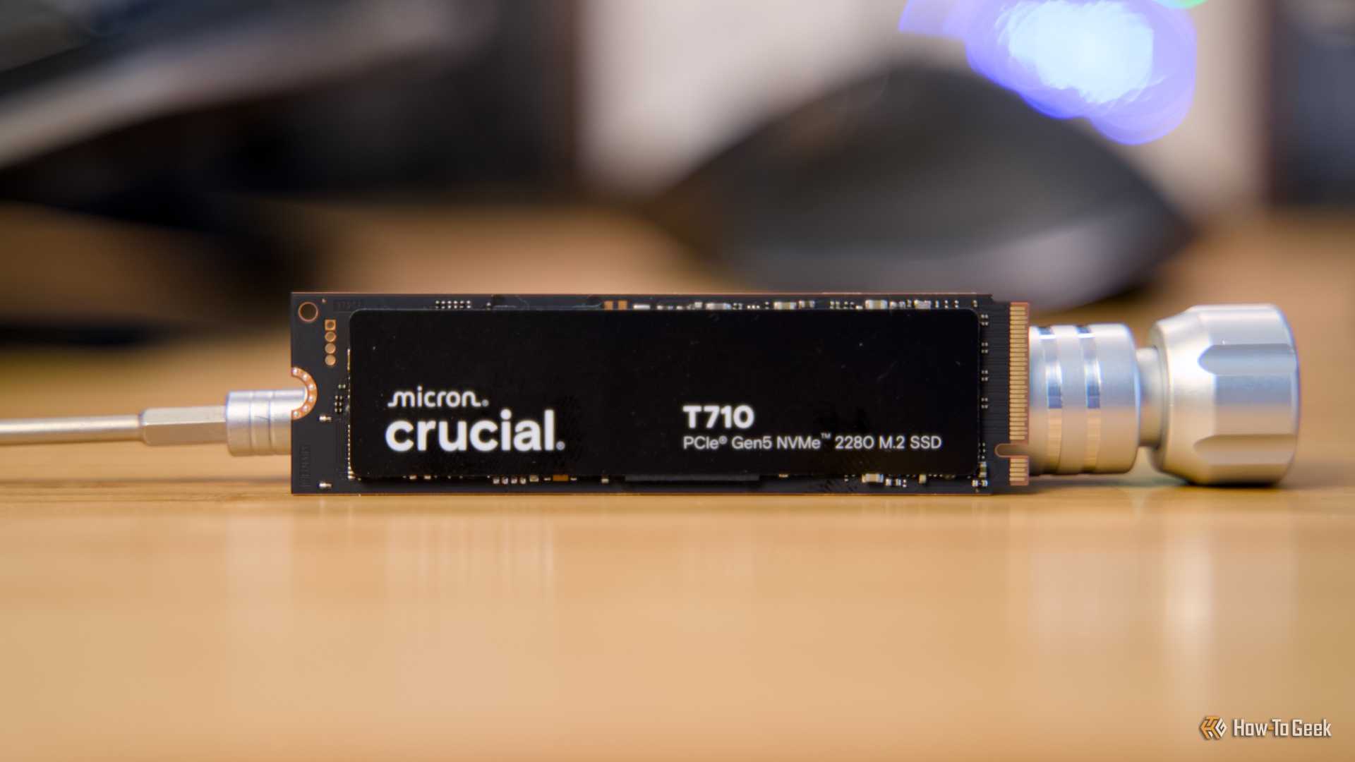 The Crucial T710 NVMe SSD propped up on a desk by a metal screwdriver.