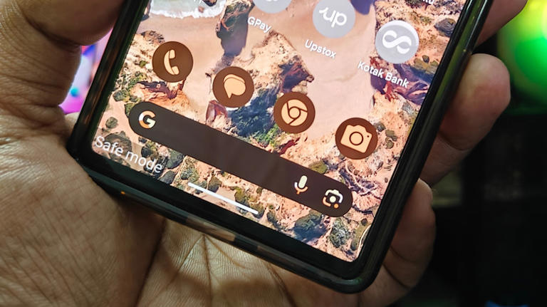 A person holding an Android phone with safe mode enabled