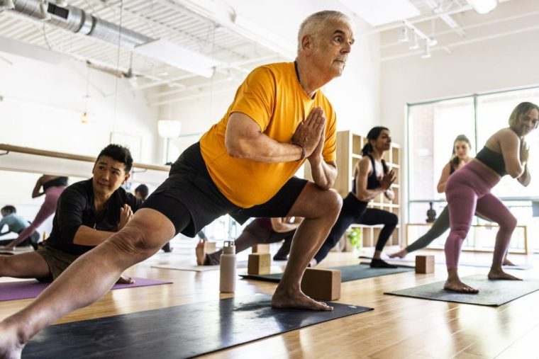 Older man performs a lunge in a yoga class
