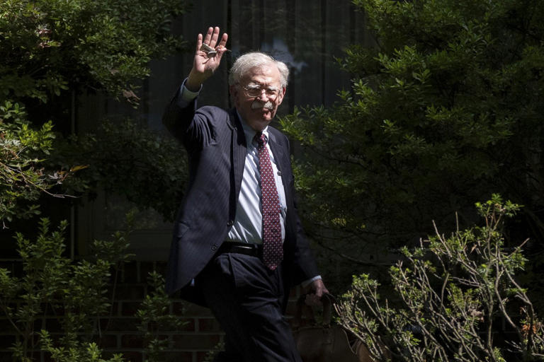 FILE - Former national security adviser John Bolton waves as he arrives at his house Aug. 22, 2025, in Bethesda, Md. (AP Photo/Manuel Balce Ceneta, File)
