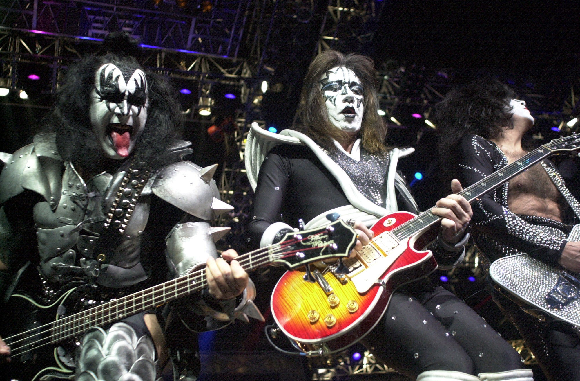 Ace Frehley (i midten) i karakteristisk Kiss-sminke sammen med bandkompisene Gene Simmons (til venstre= og Paul Stanley på konsert i Detroit i 2000. Arkivfoto: Paul Warner / AP / NTB