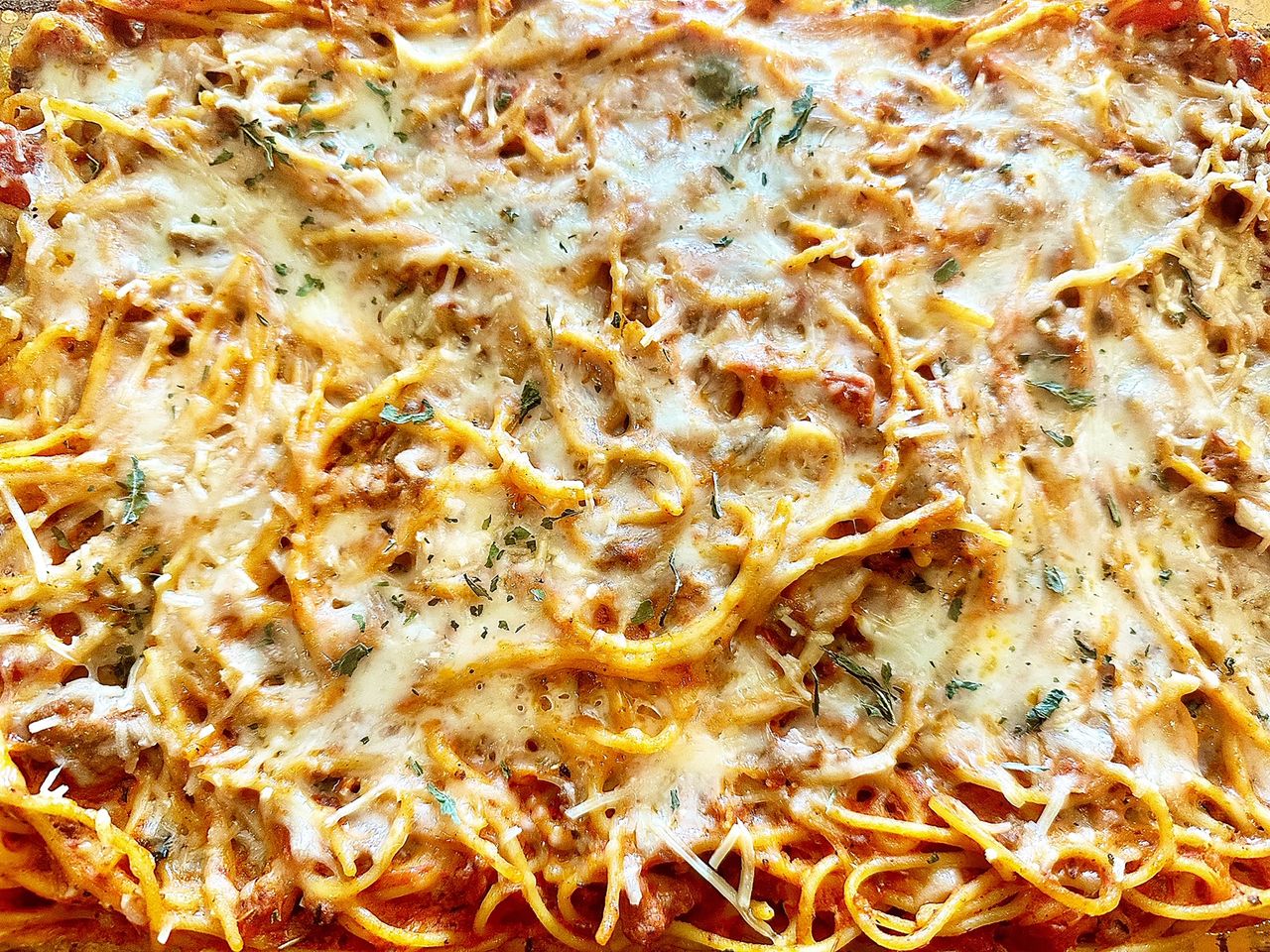 cream cheese spaghetti casserole topped with cheese