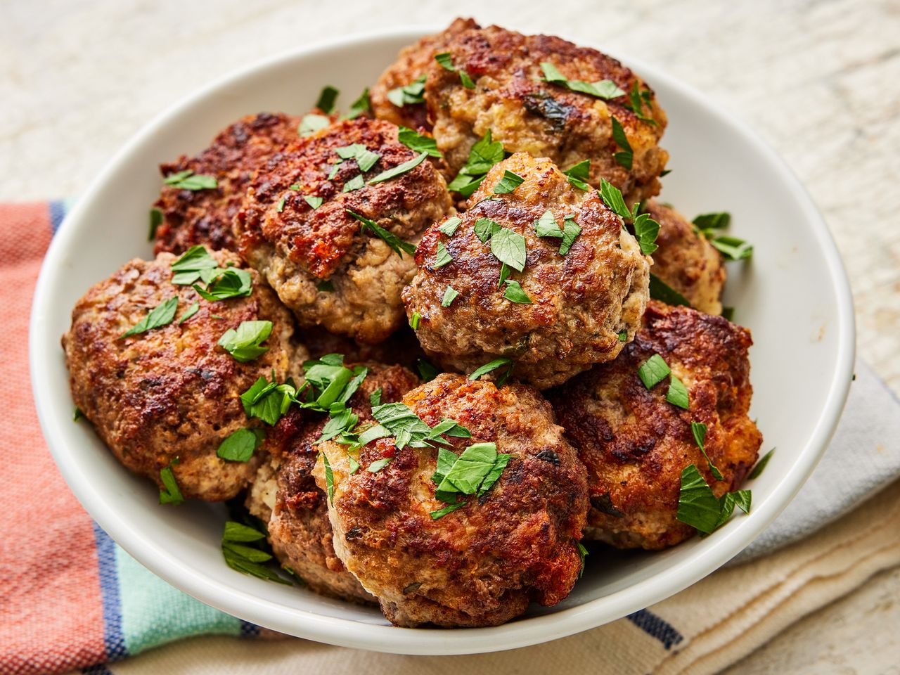 A bowl of cooked meatballs topped with parsley