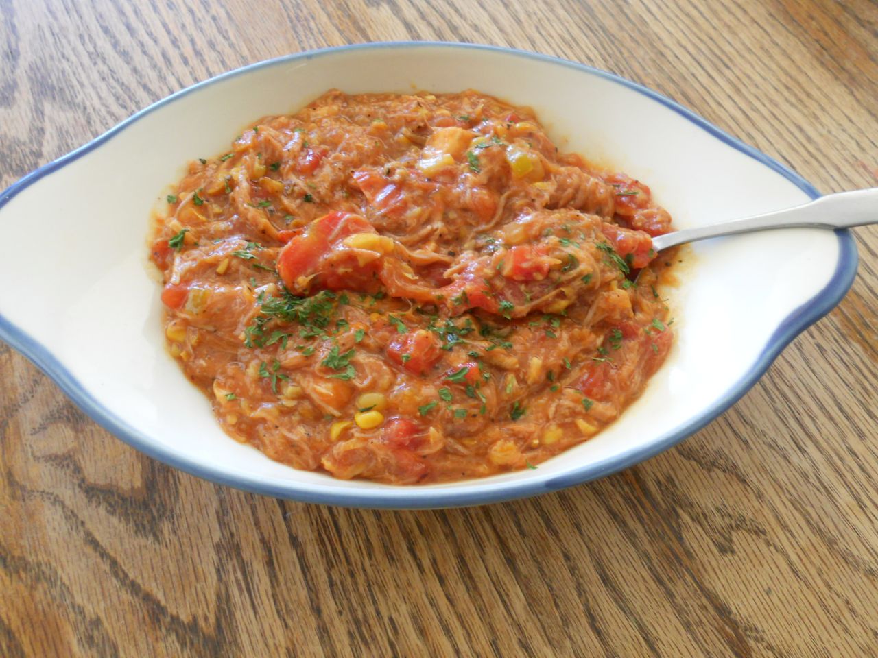 A bowl of a tomatobased dish with a spoon garnished with herbs