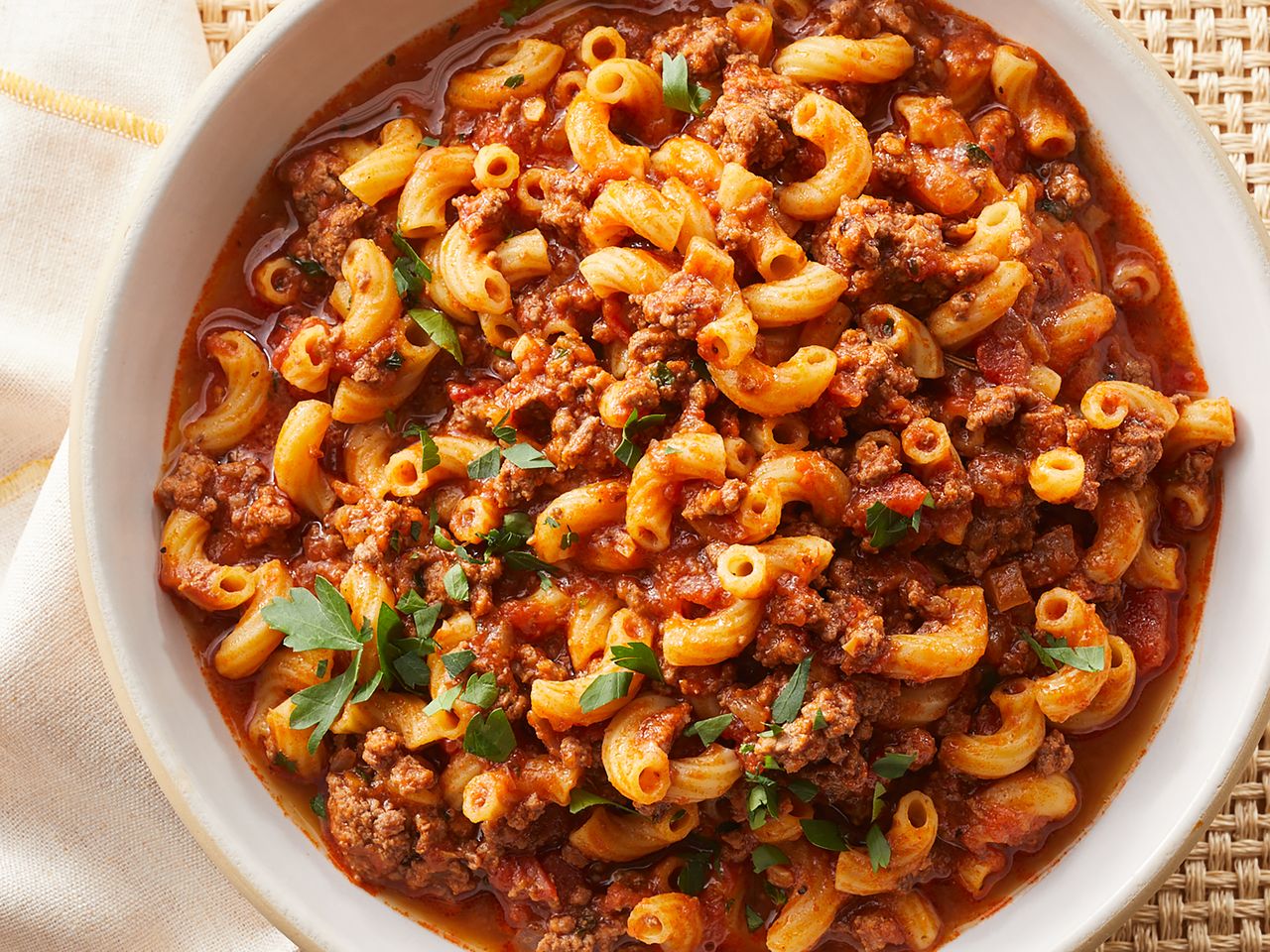 Plate of macaroni pasta with minced meat in sauce garnished with parsley