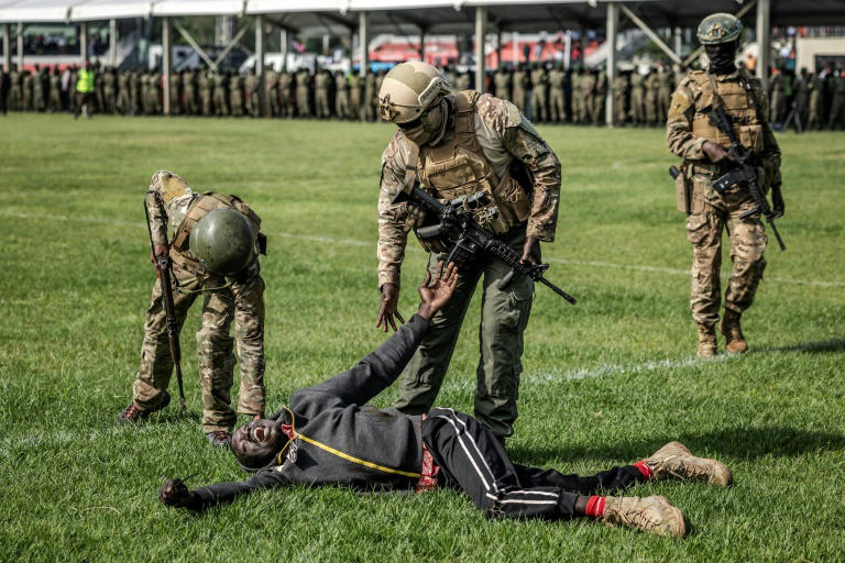 Des membres des forces de l'ordre du Kenya assistent un partisan de l'opposant Raila Odinga, dans le stade où son corps est exposé, à Kisumu, le 18 octobre 2025