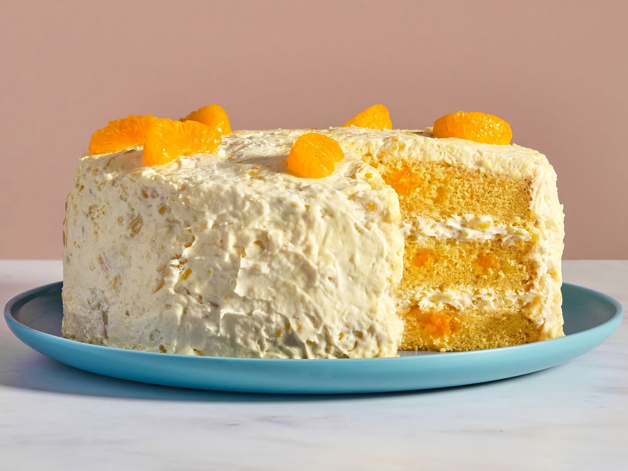 a low angle view looking into a pig pickin cake, topped with mandarin oranges, with a slice removed.