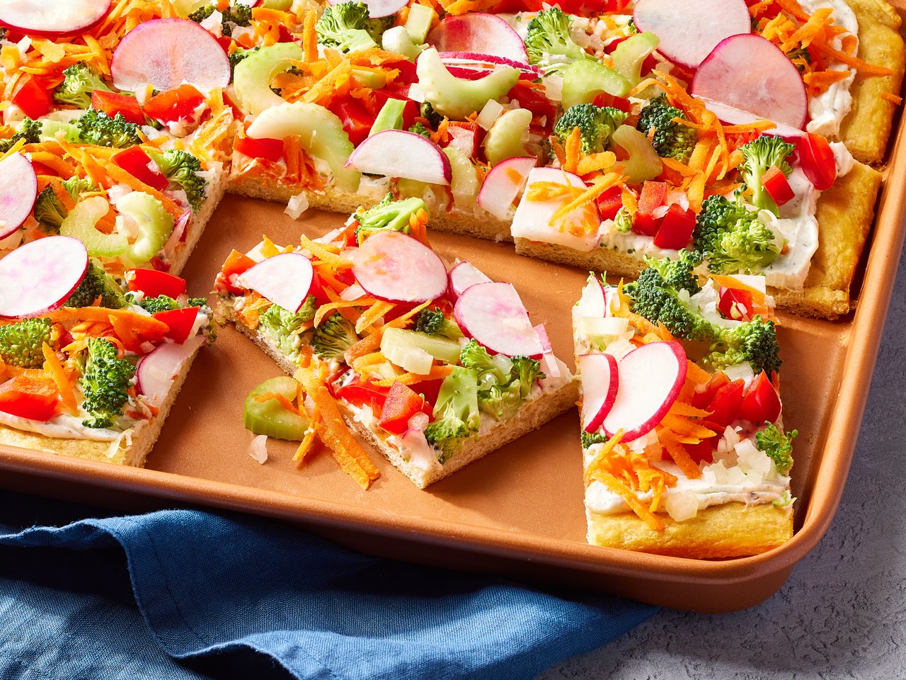 A baking sheet with square slices of veggie pizza