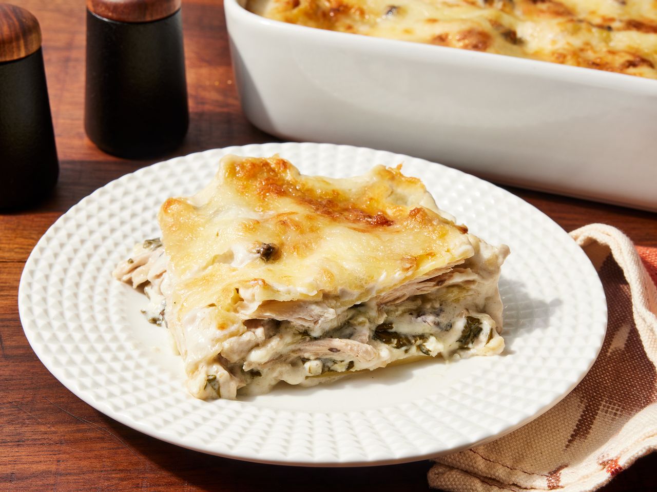 Slice of Chicken and Spinach Alfredo Lasagna on a white plate