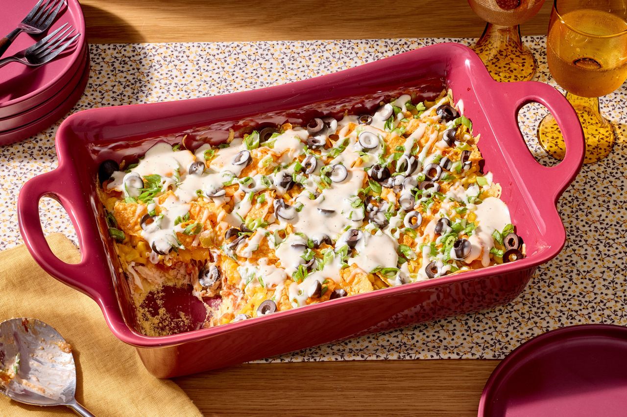 A casserole dish containing a layered baked dish with toppings such as sliced olives and vegetables