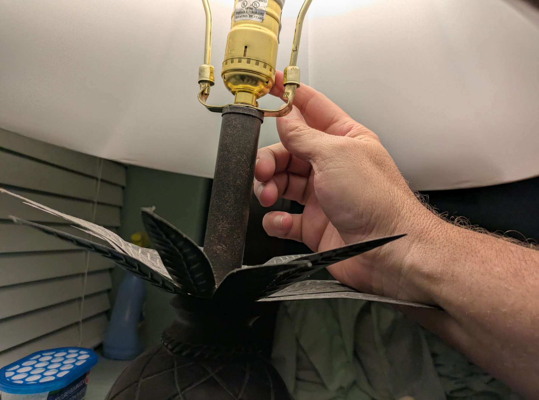 Hand adjusting lampshade, highlighting a plant-inspired lamp design with a bulb socket