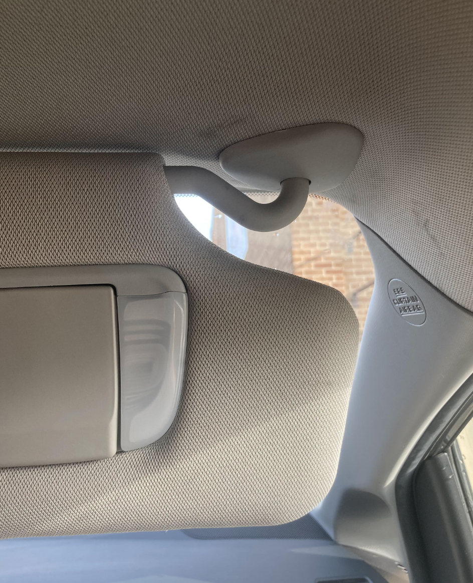 Car interior with a closed sun visor and a ceiling-mounted grab handle