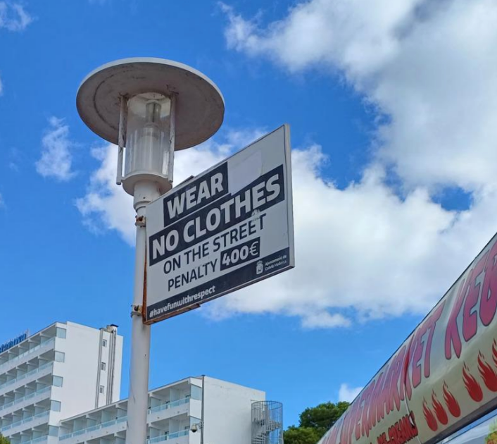 Sign reads: "Wear no clothes on the street. Penalty 400€."