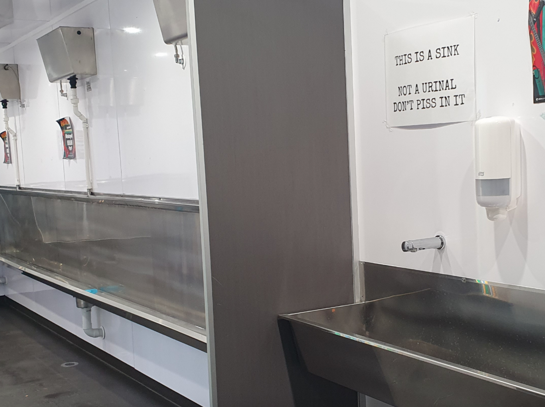 Indoor area with multiple stainless steel sinks. Sign above reads,