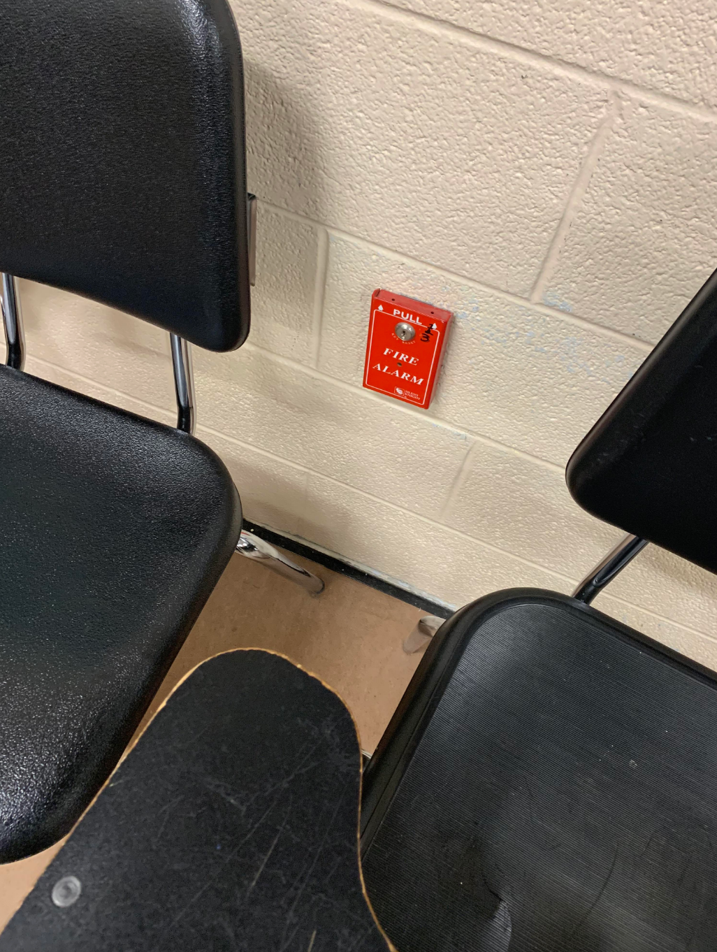 Two chairs and a desk beside a wall with a fire alarm mounted on it