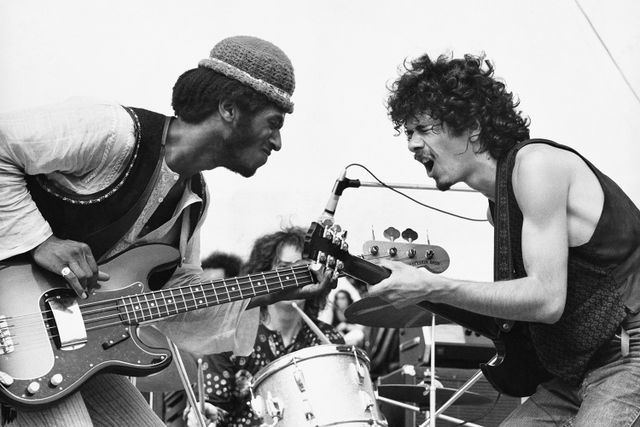 American Rock musicians David Brown (1947 - 2000) (left), on bass guitar, and Carlos Santana, on guitar, both of the group Santana, perform onstage during the Woodstock music festival, Bethel, New York, August 16, 1969. Mostly obscured between them is Michael Shrieve, on drums.
