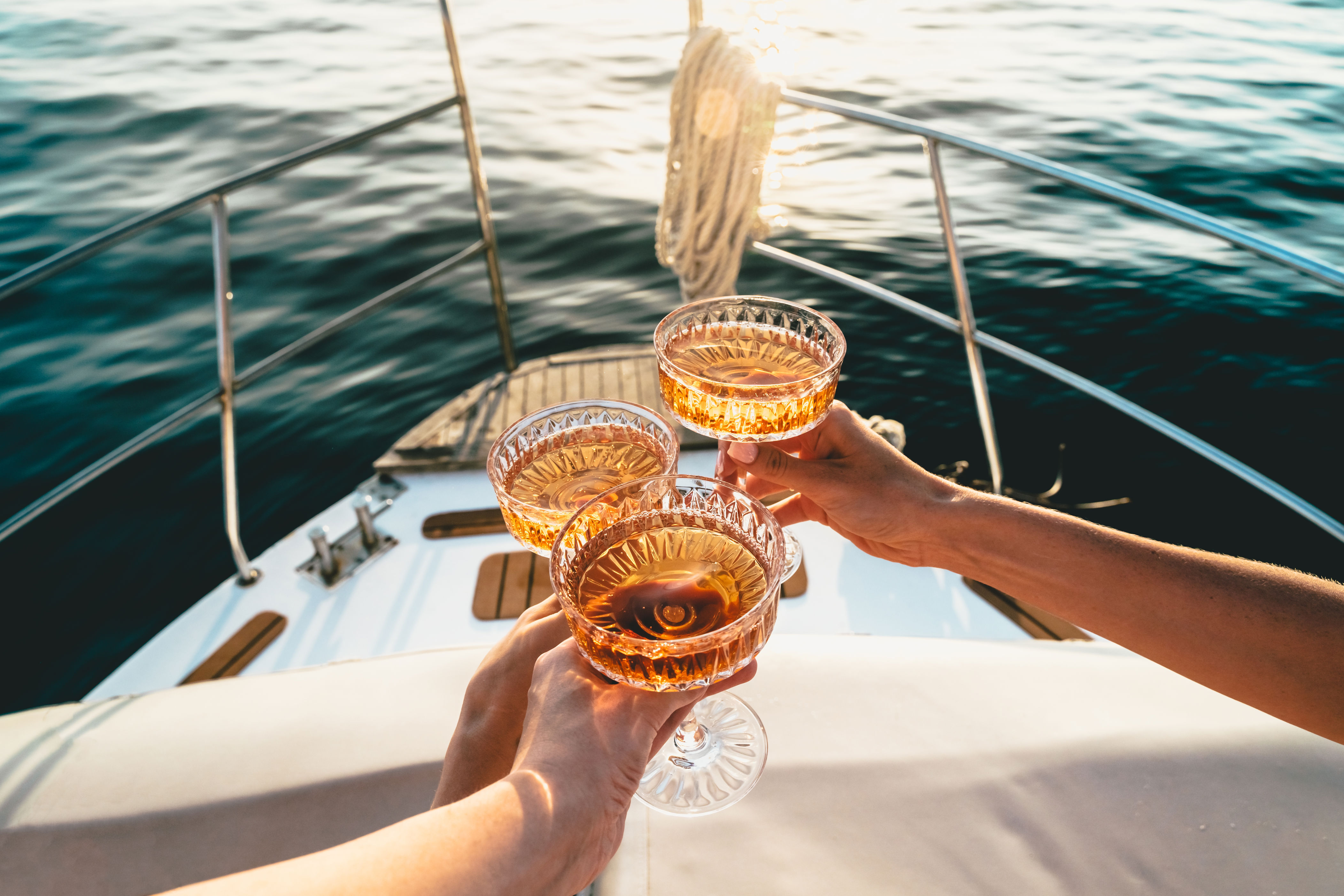 People on a boat toasting with champagne glasses against a sea backdrop