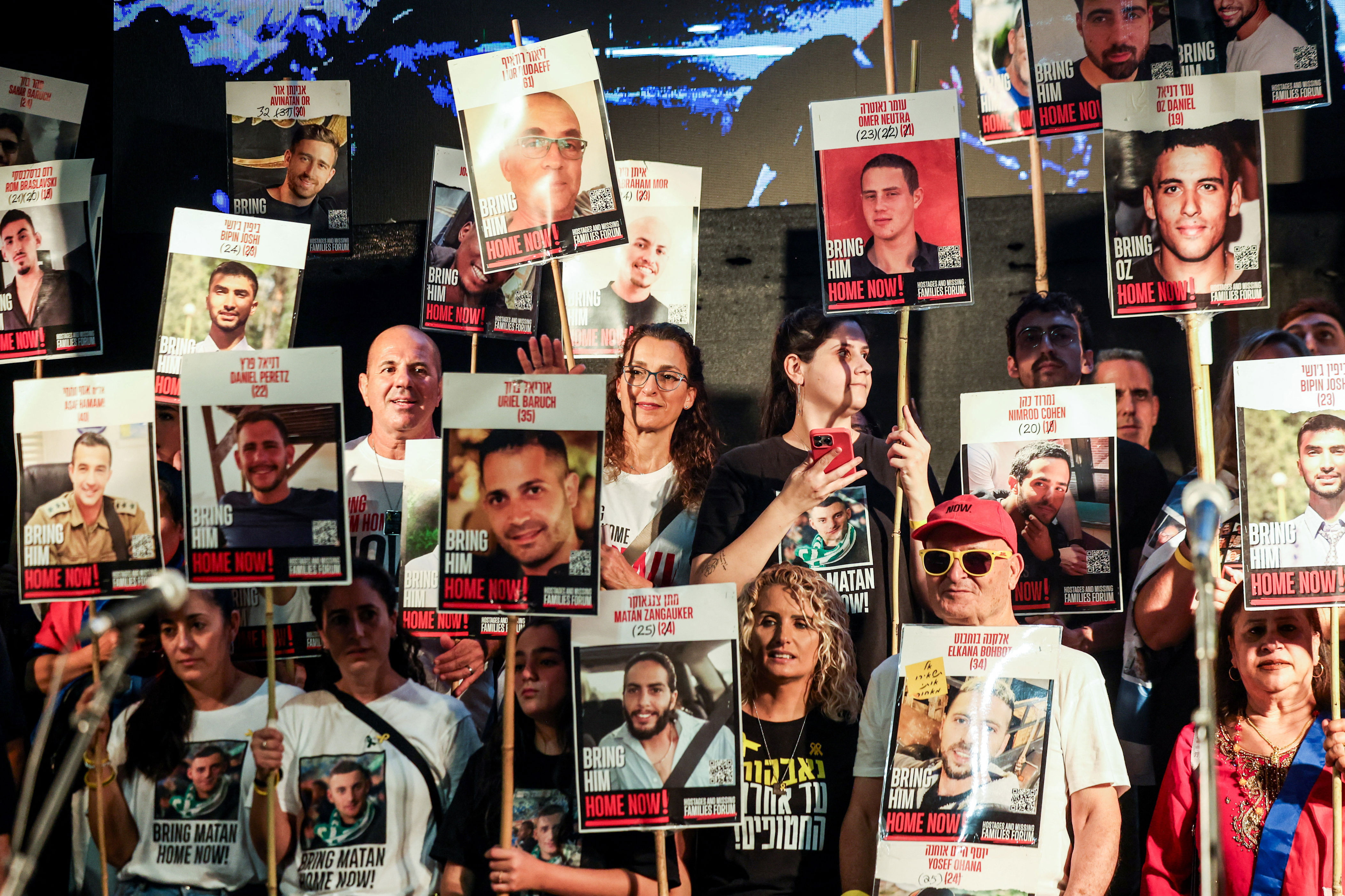People hold placards with pictures of hostages in Tel Aviv (REUTERS)