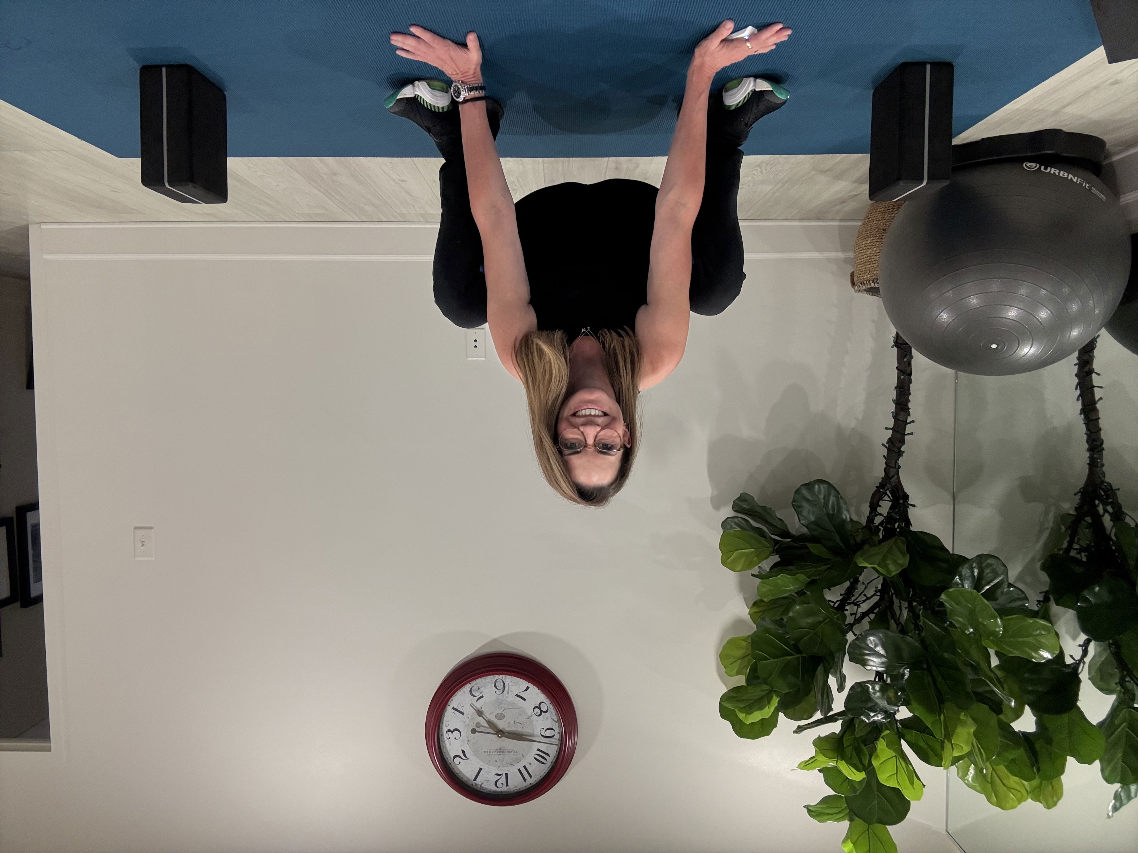 An employee at Femina physical therapy performs a deep squat. Her knees and hips are bent and her hands rest on the floor.