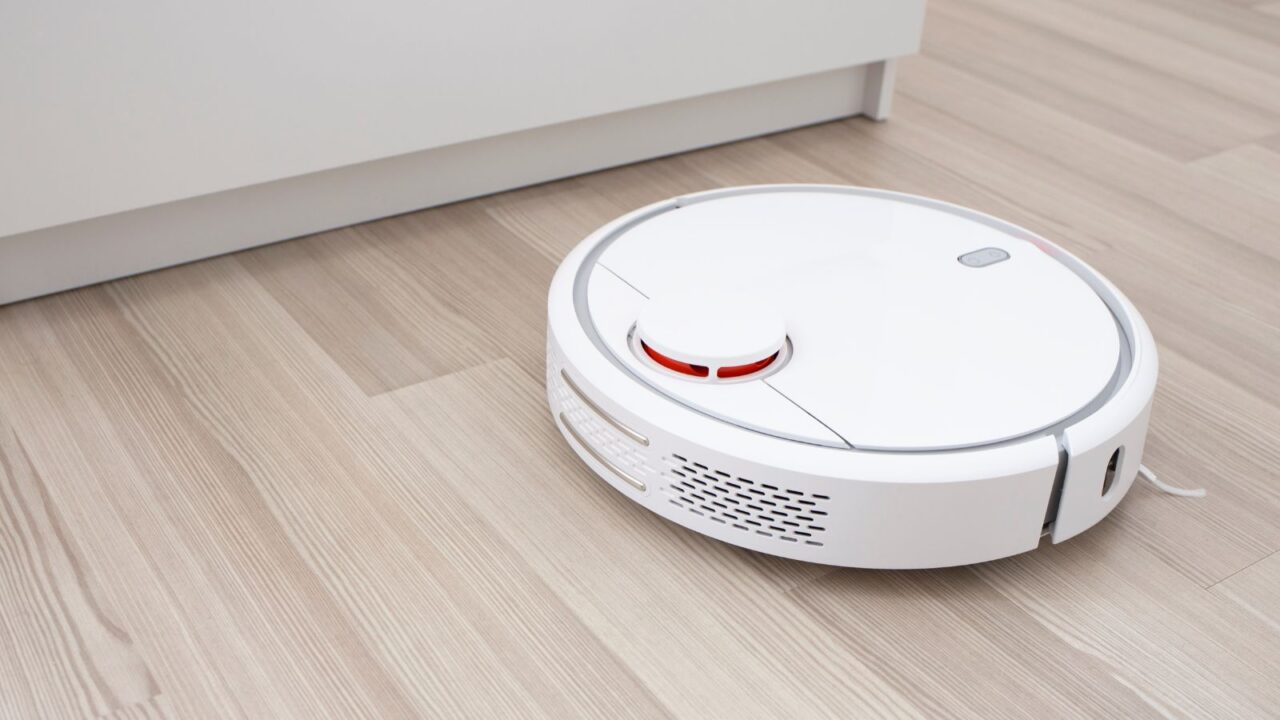 Picture of a white robot vacuum cleaner on the floor in the living room.