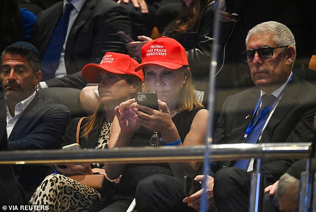 People wearing hats reading: 'Trump The Peace President' sit inside the Knesset