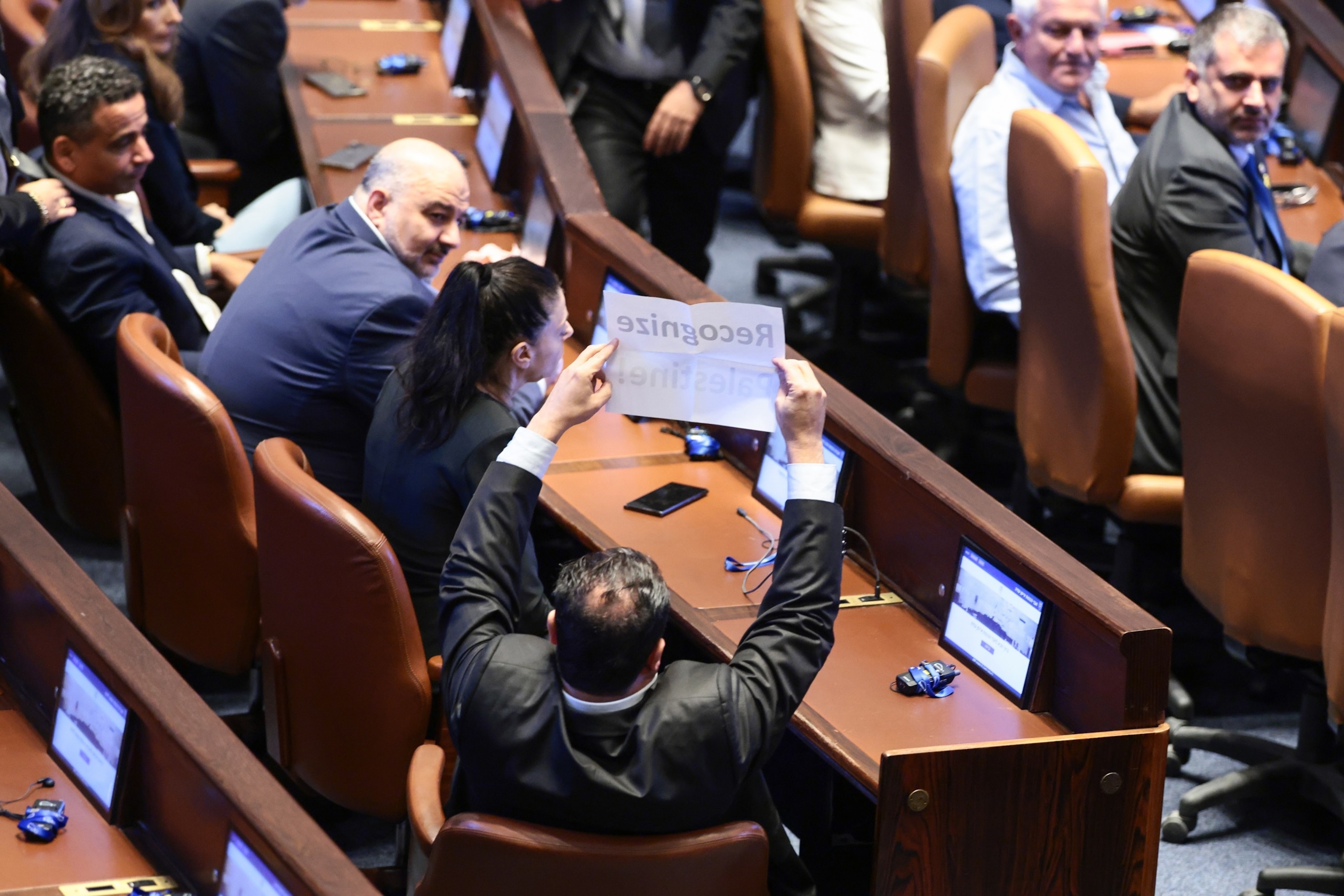 Evelyn Hockstein/Pool via Getty Images - PHOTO: An Israeli member of parliament holds a placard that reads: 'Recognize Palestine!' at the Knesset, Israel's parliament, during U.S. President Donald Trump's address, October 13, 2025 in Jerusalem.