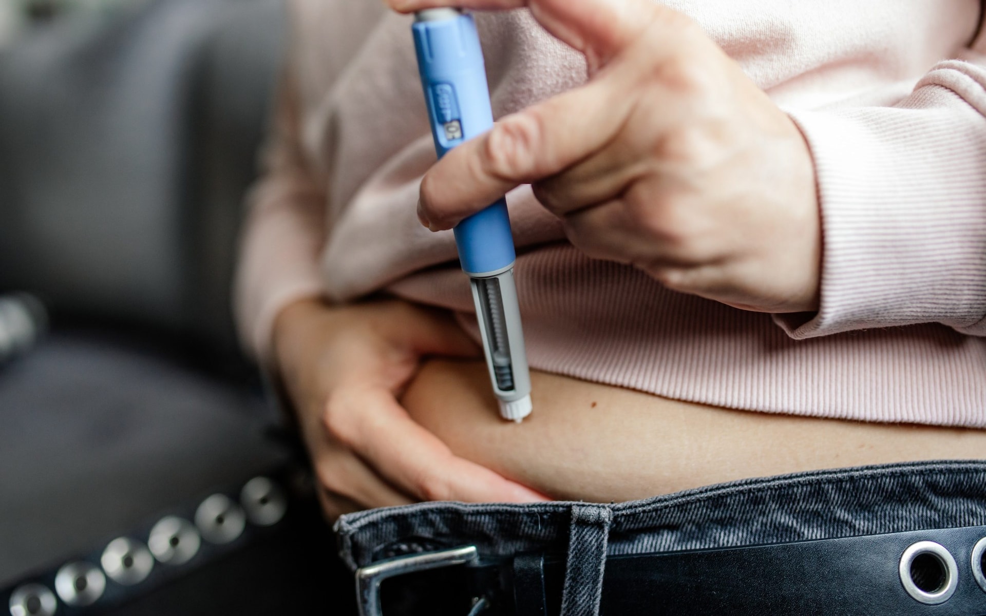 A woman performs a self-injection into her abdomen