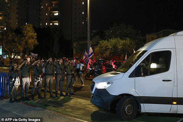 Israeli soldiers salute as vehicles transporting the bodies of four hostages handed over following a ceasefire and prisoner exchange deal between Israel and Palestinian factions in Gaza, arrive to the National Center for Forensic Medicine in Tel Aviv on October 13