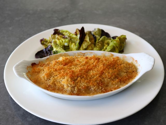 oval casserole for one of chicken cordon bleu on white plate with red leaf baby lettuce
