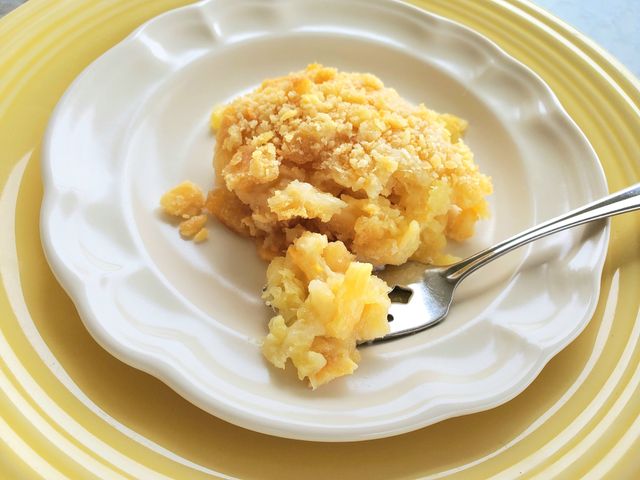 close up view of a piece of Easy Pineapple Casserole on a white plate with fork