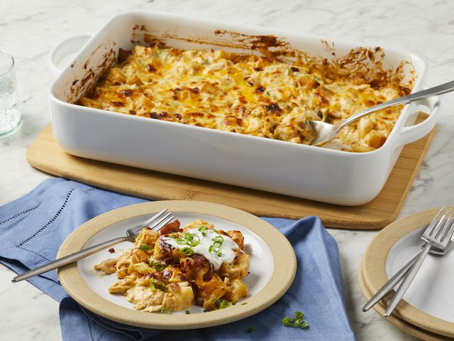 looking at a serving of loaded chicken and potato casserole on a plate with remaining in casserole dish behind