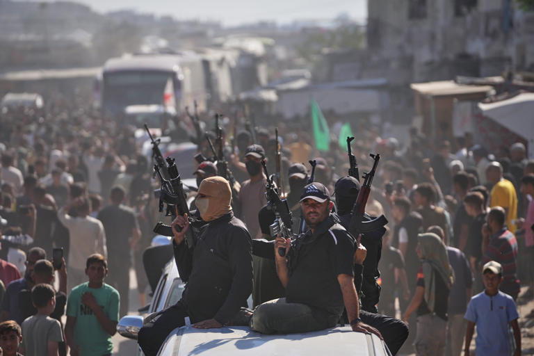 Hamas gunmen escort buses carrying freed Palestinian prisoners on Monday (AP)