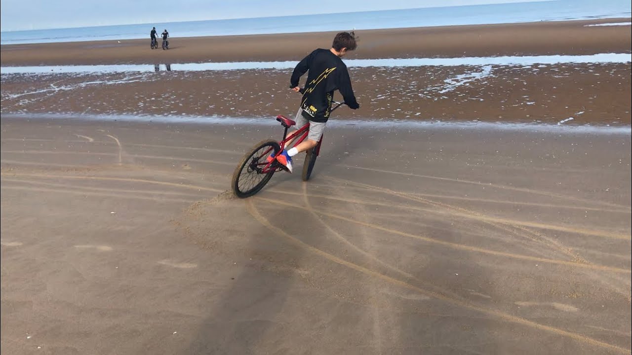 Riders perform drifting maneuvers across sandy terrain