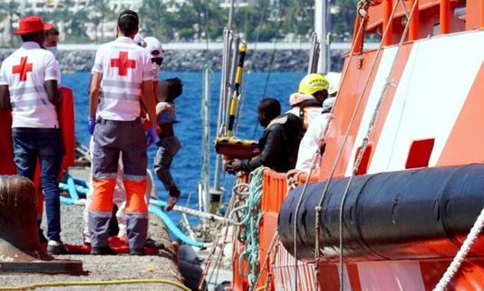 Red Cross staff help migrants disembark from a lifeboat in the Canary Islands