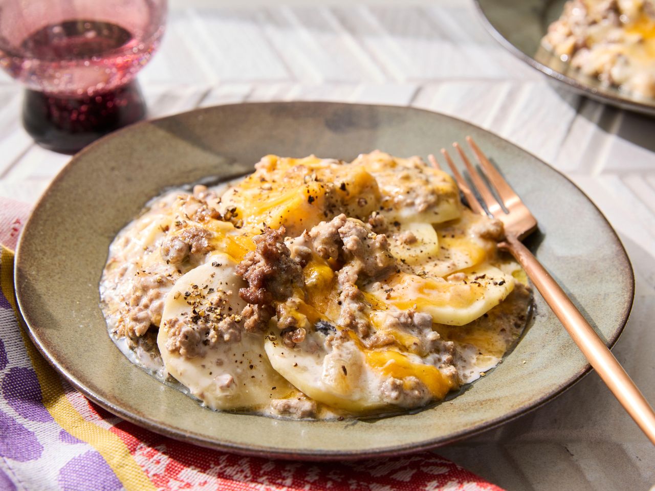 Slow cooker cowboy casserole on a plate, topped with melted cheese and served with a fork.