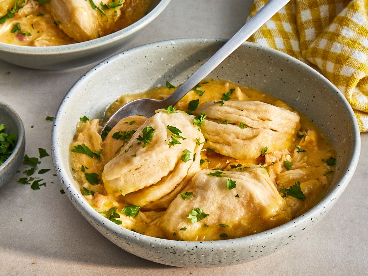 close up view of slow cooker chicken and dumplings in bowls, with a spoon
